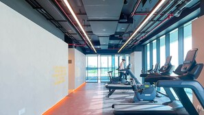 A modern gym with treadmills, stationary bikes, and a large window offering a view of the outdoors. - Spacious 2B in Sobha Creek Vistas Dubai (Dubai)