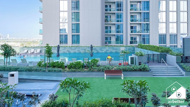 A modern building with a rooftop pool, lounge chairs, and a small garden area. - Spacious 2B in Sobha Creek Vistas Dubai (Dubai)