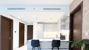 A modern kitchen with white cabinetry, a central island with stools, and a built-in oven. - Spacious 2B in Sobha Creek Vistas Dubai (Dubai)