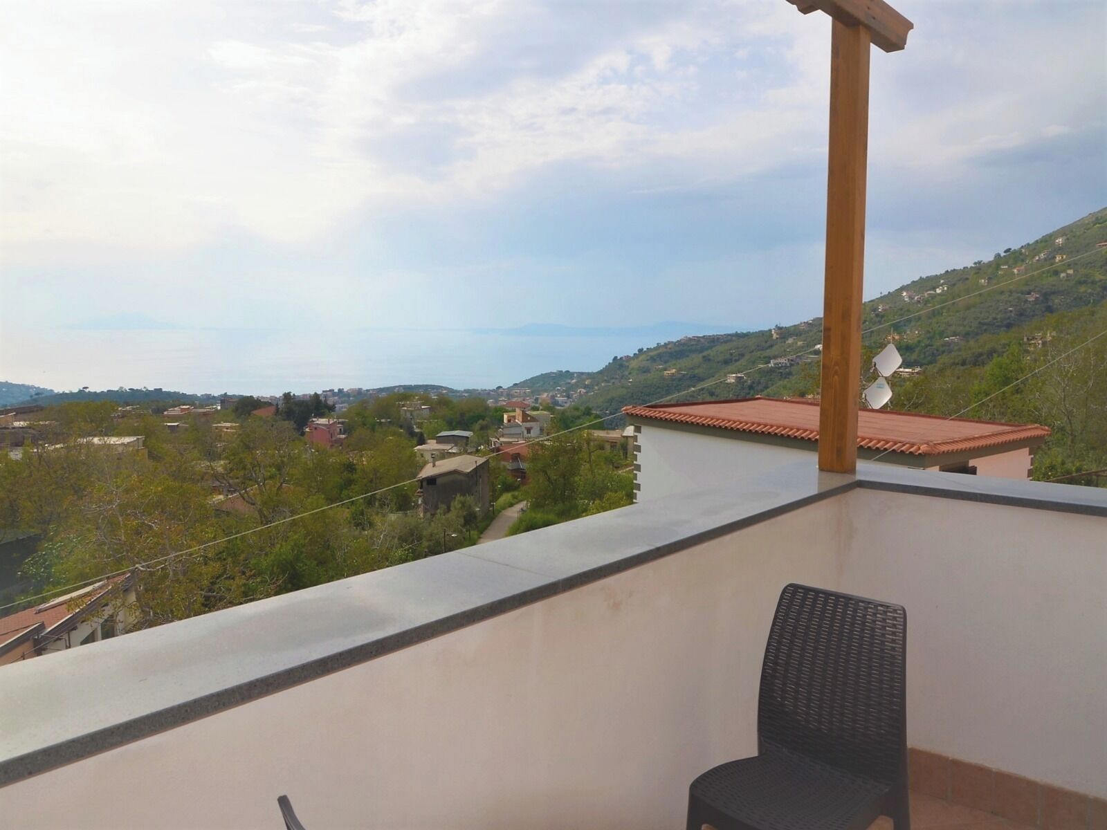 A balcony with a view of a hilly landscape and buildings.