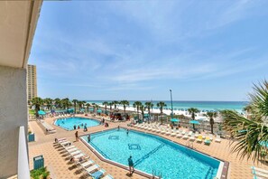 A resort with two swimming pools, beach umbrellas, lounge chairs, and a view of the ocean. - The Summit 312 (Panama City Beach)
