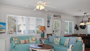 A cozy living room with a teal sofa, a wooden coffee table, and a ceiling fan. - Palmetto Breeze (Port St. Joe)
