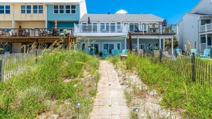 Una propiedad frente a la playa con un camino pavimentado que lleva a un edificio con balcón.
