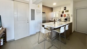 Una cocina moderna con una isla central, taburetes de bar, un refrigerador y una cafetera.