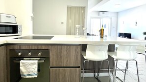 Una cocina moderna con horno empotrado, microondas y una isla grande con taburetes de bar.