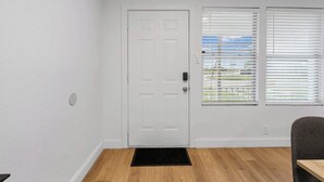 A room with a white door, a black doormat, and a window with blinds. - TCU Area Home - Blue Bonnet Circle (Fort Worth)
