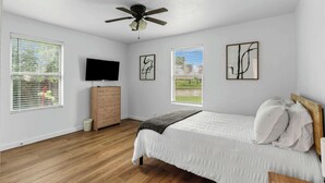 A bedroom with a bed, a ceiling fan, a dresser, and a television on the wall. - TCU Area Home - Blue Bonnet Circle (Fort Worth)