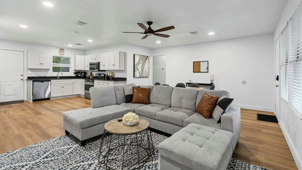 A modern living room with a sectional sofa, a coffee table, and a ceiling fan. - TCU Area Home - Blue Bonnet Circle (Fort Worth)