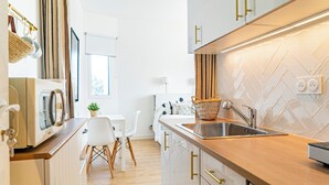 A modern kitchen with white cabinetry, a wooden countertop, and a herringbone tile backsplash. - Elegant Apt between sea, ponds and nature, 5 minutes from beaches, direct access to streetcar. (Pérols)