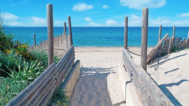 A wooden beach path leading to the sea with clear skies. - Elegant Apt between sea, ponds and nature, 5 minutes from beaches, direct access to streetcar. (Pérols)
