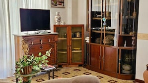 A living room with a television, wooden cabinet, and a glass display cabinet. - Sicilian Apt in Donnalucata-sleeps 4- 2 Min Beach (Scicli)