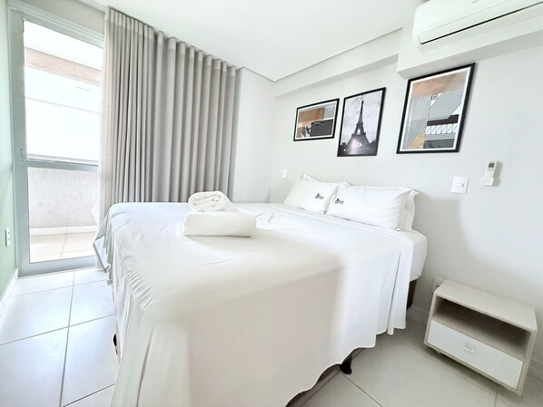 A hotel room with a bed, a bedside table, a window with curtains, and wall art. - iFlat Brookfield Towers BT3004 (Goiania)