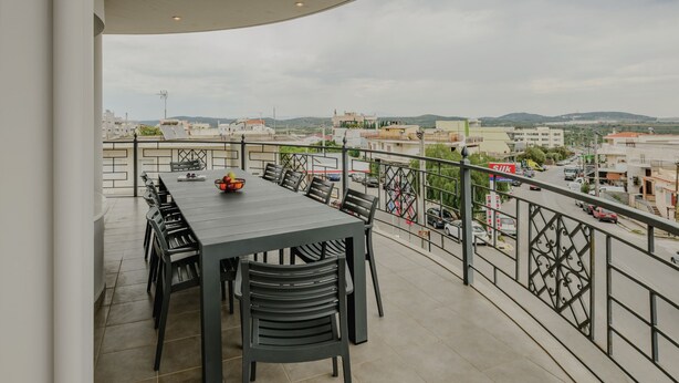 A balcony with a table and chairs, a bowl of fruit, and a view of the cityscape and hills in the background. - Jaax Apartment Airport by Airstay (Spata-Artemida)