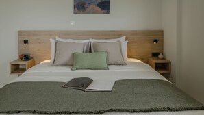 A neatly made bed with a green blanket, two bedside tables with lamps, and a painting on the wall. - Jaax Apartment Airport by Airstay (Spata-Artemida)