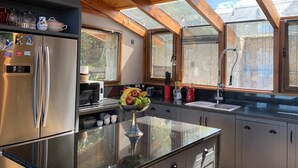 A modern kitchen with a large refrigerator, microwave, and a fruit bowl on the counter. - Tanière. Contemporary design house. Breathtaking lake view. (Villa La Angostura)