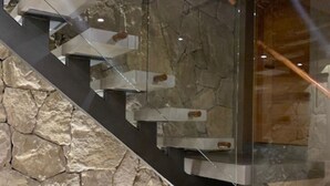 A staircase with a stone wall and glass panels. - Tanière. Contemporary design house. Breathtaking lake view. (Villa La Angostura)