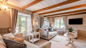 A spacious living room with a sofa, a coffee table, and a TV mounted on the wall. - 3 Bed in Brixham (oc-r31919) (Brixham)