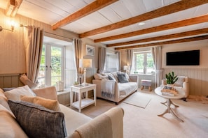 A spacious living room with a sofa, a coffee table, and a TV mounted on the wall.
