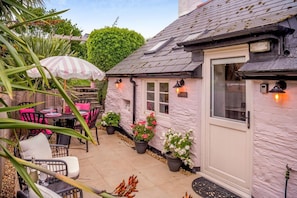 A cozy patio area with outdoor seating, a white door, and potted plants.