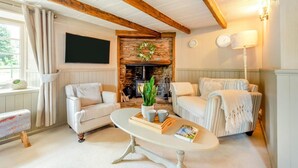 A cozy living room with a fireplace, two sofas, a coffee table, and a television. - 3 Bed in Brixham (oc-r31919) (Brixham)
