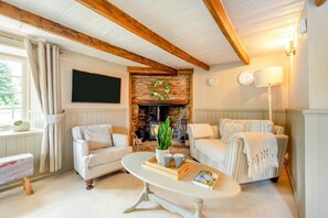 A cozy living room with a fireplace, two sofas, a coffee table, and a television.