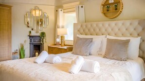 A neatly made bed with rolled towels, a tufted headboard, a round mirror, and a small bedside table with a lamp. - 3 Bed in Brixham (oc-r31919) (Brixham)