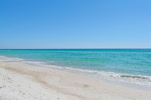 Een strand met helder turquoise water en wit zand.