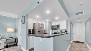 A modern kitchen with white cabinets, stainless steel appliances, and a central island.