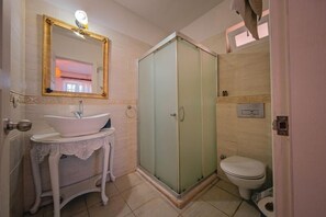 Casa de banho com uma pia branca, toucador e cabine de duche em vidro.