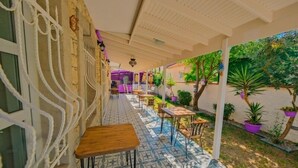 Un espacio al aire libre cubierto con mesas y sillas, suelo estampado y plantas en macetas.