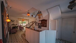 Una cocina amplia con una isla central, un área de comedor con sofá y sillas, y una escalera que lleva a un nivel superior.