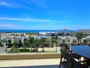 Bairro residencial com casas modernas, céu azul límpido e vista para o oceano.