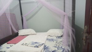 Una cama individual con dosel, ropa de cama blanca y un cojín estampado con motivos florales.