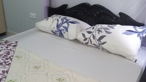 Una cama con una colcha blanca y dos almohadas con estampado floral.