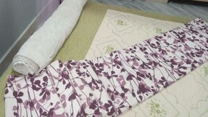 Un dormitorio con una cama cubierta por una colcha estampada, un dosel y un almohadón con diseño de pavo real.