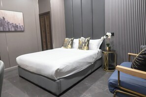 Relax in a stylish room with a large bed, side table, and comfortable armchair.