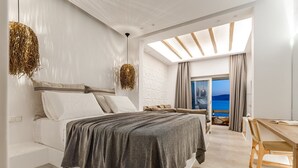 Ein modernes Schlafzimmer mit einem großen Bett, einem Holztisch und Blick aufs Meer.