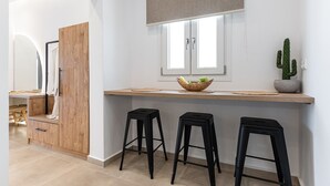 Eine moderne Küche mit einer Holz Arbeitsplatte, zwei schwarzen Hocker, einem Fenster mit Blick und einer Kakteenpflanze.
