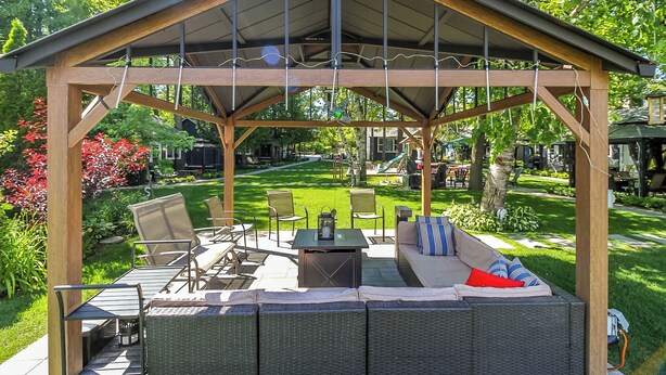 A covered outdoor seating area with a wooden pergola, a sofa, chairs, and a table. - Charming 4-bedroom house with AC, WiFi in brilliant Wasaga Beach (Wasaga Beach)