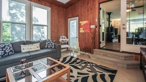 A cozy living room with a wooden ceiling, a gray sofa with patterned cushions, a glass coffee table, and a black-and-white rug. - Charming 4-bedroom house with AC, WiFi in brilliant Wasaga Beach (Wasaga Beach)