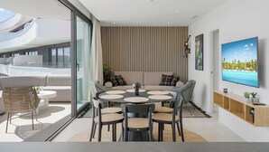 Una sala de estar moderna con una mesa de comedor redonda, sofás y una televisión.