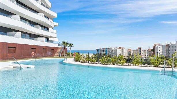 Un hotel moderno con piscina, una escalera que lleva a los pisos superiores y vista al mar.