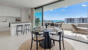 Cocina moderna con armarios blancos, una isla central y un comedor con una mesa redonda y sillas.