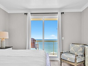 Ein Schlafzimmer mit einem großen Bett, einem Sessel und einem Balkon mit Meerblick.