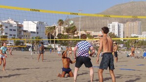 Partido de voleibol de playa con una red que dice 'COPAYA' y montañas al fondo.