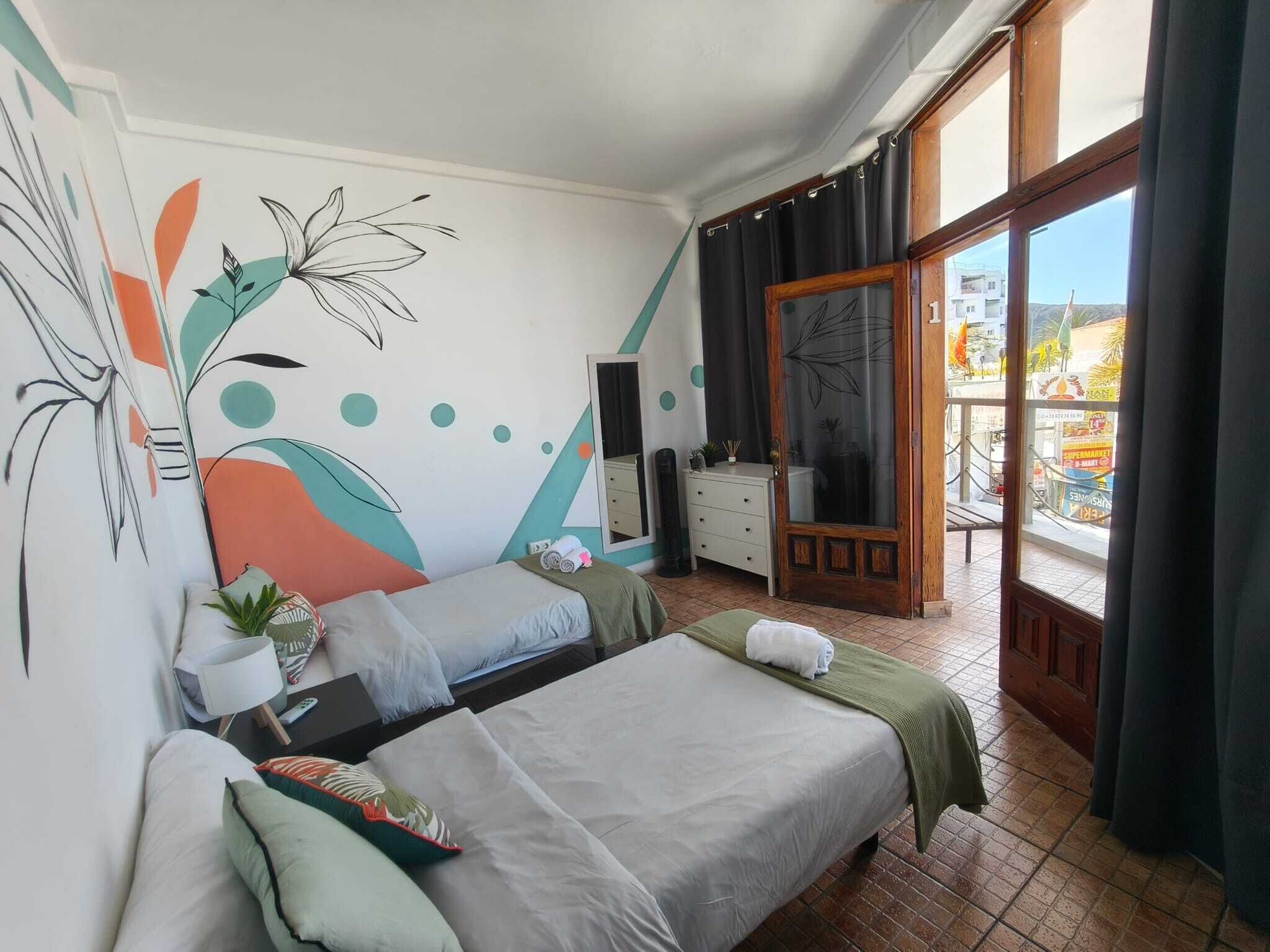 A bedroom with two beds, a dresser, a mirror, and a view of the outside.