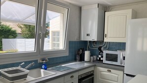 Una cocina con armarios blancos, horno empotrado, microondas y ventana con vistas al exterior.