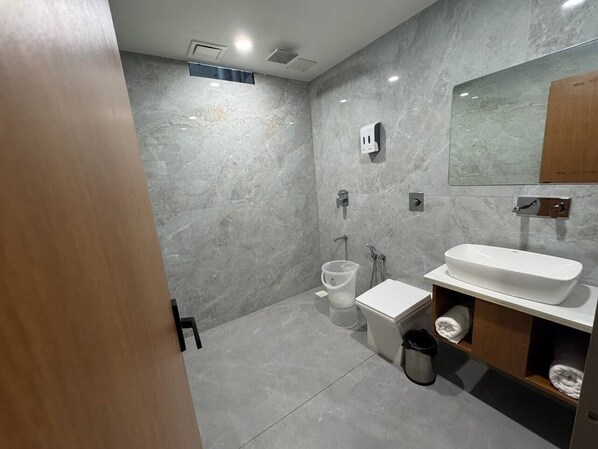 Uma casa de banho moderna com parede de mármore, lavatório branco, sanita e zona de duche.