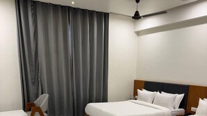 A hotel room with two beds, a desk, and a chair. - Hotel Madhukta Inn (Somnath)