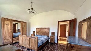 Une chambre à coucher avec un lit en bois, une commode, une table de chevet et un miroir.